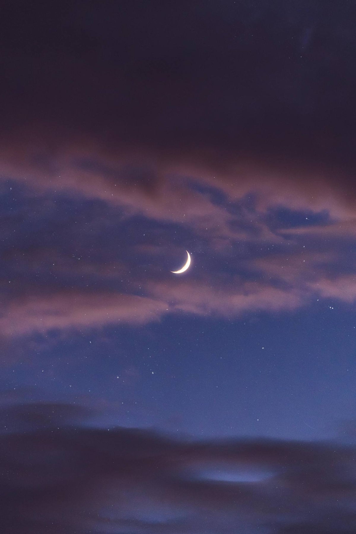 Crescent moon in a dark blue sky with purple clouds