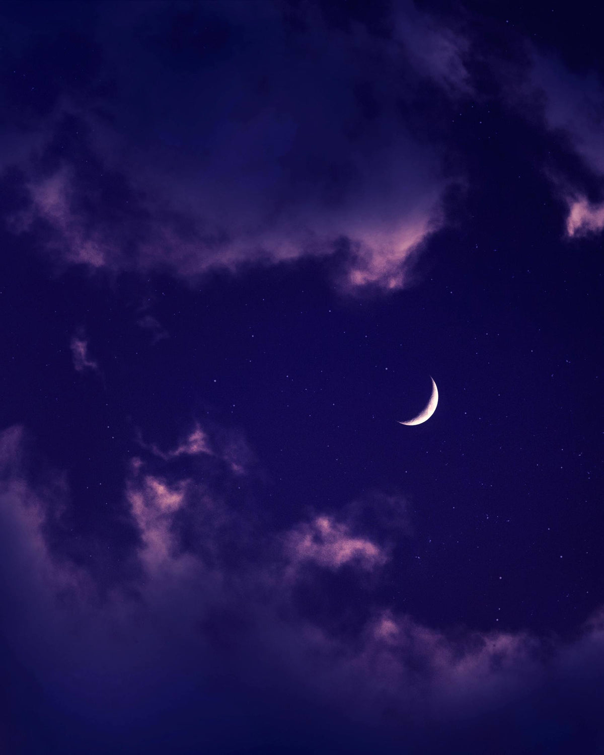 Half-moon in a purple night sky with clouds
